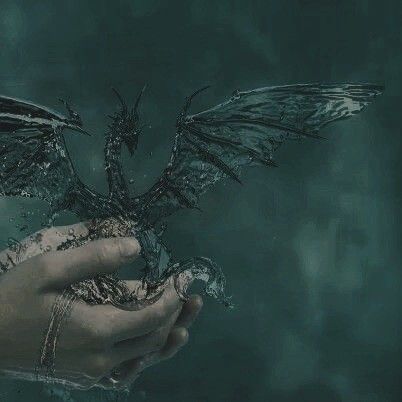 a hand holding a bird with water splashing out of it's wings and body