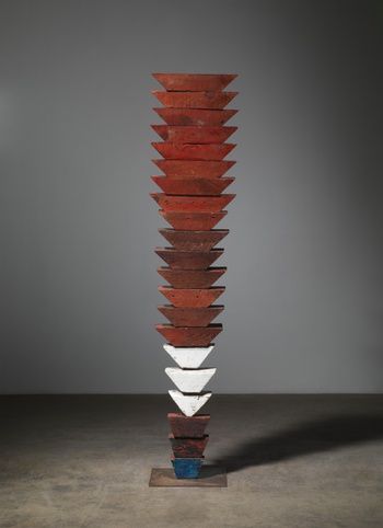 a tall wooden sculpture sitting on top of a cement floor