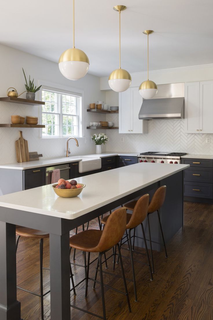 a kitchen with an island, sink and several hanging lights over the counter top in front of it