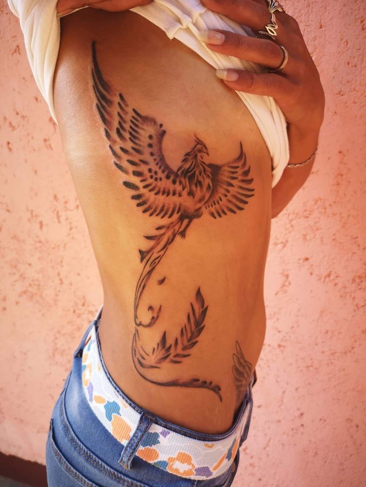 a woman with a bird tattoo on her stomach holding a cell phone to her ear