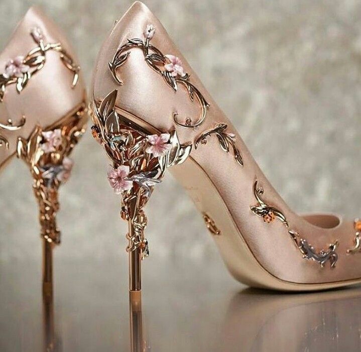 a pair of high heeled shoes with flowers on the side and gold colored heels