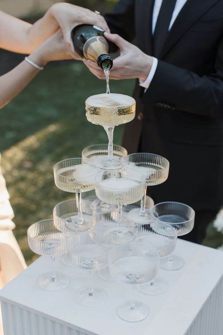 a bride and groom pouring champagne into wine glasses