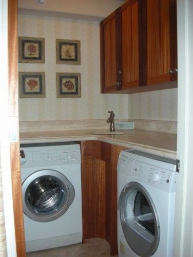 a washer and dryer in a small room with wooden cabinets on the wall