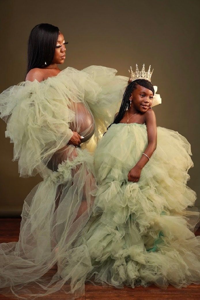 two women in gowns and tiaras posing for the camera