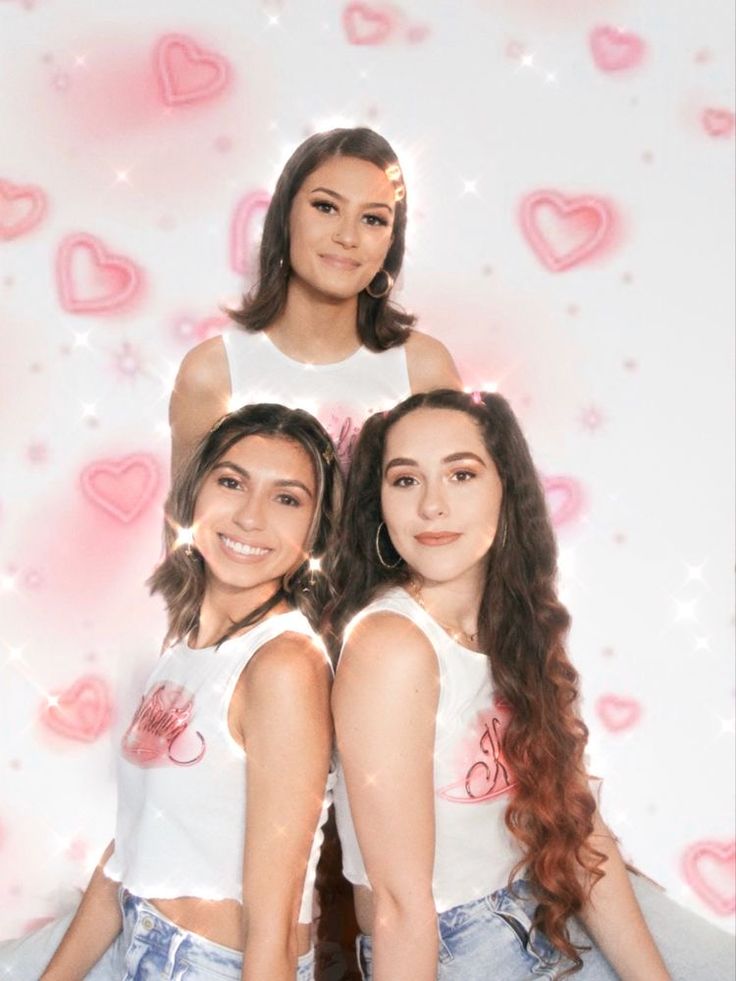 two girls are posing in front of a wall with hearts on it and one girl has her arms around the other