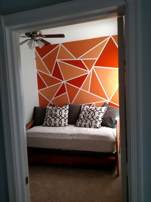 a bed sitting in the middle of a bedroom next to a wall with geometric designs on it