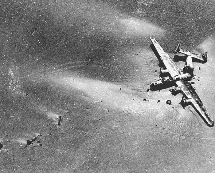 an airplane is flying in the sky over water and land, with debris scattered around it