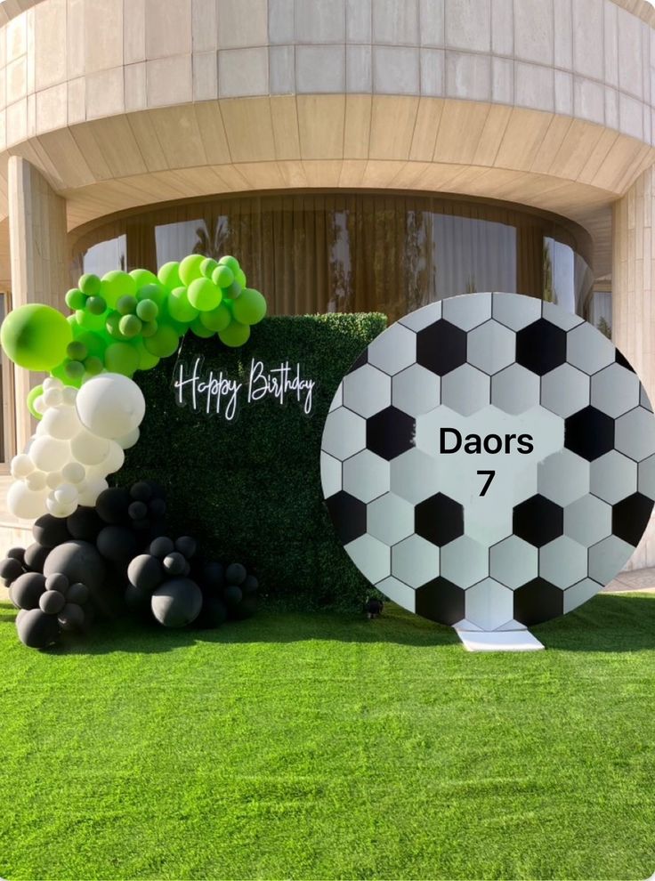 a large soccer ball sitting on top of a lush green field in front of a building