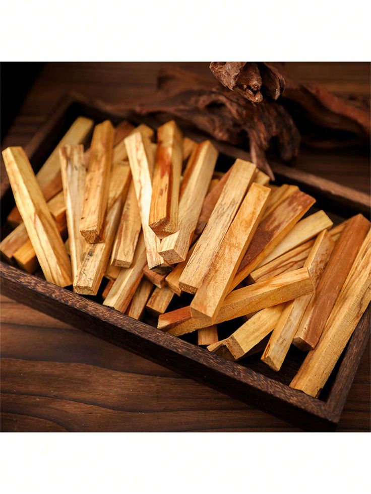 a wooden box filled with lots of cut wood sticks on top of a wooden table