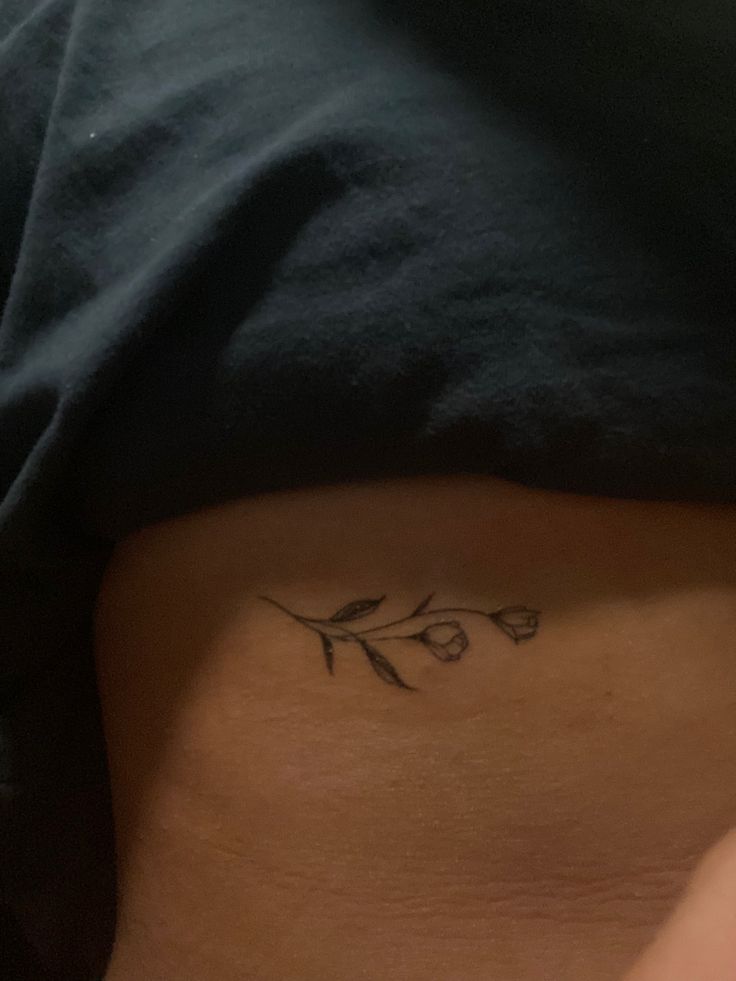 a woman's stomach with a small flower tattoo on the side of her belly