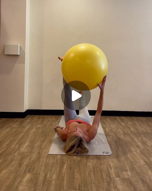 a woman is doing exercises with an exercise ball on her back while holding the balance ball up above her head