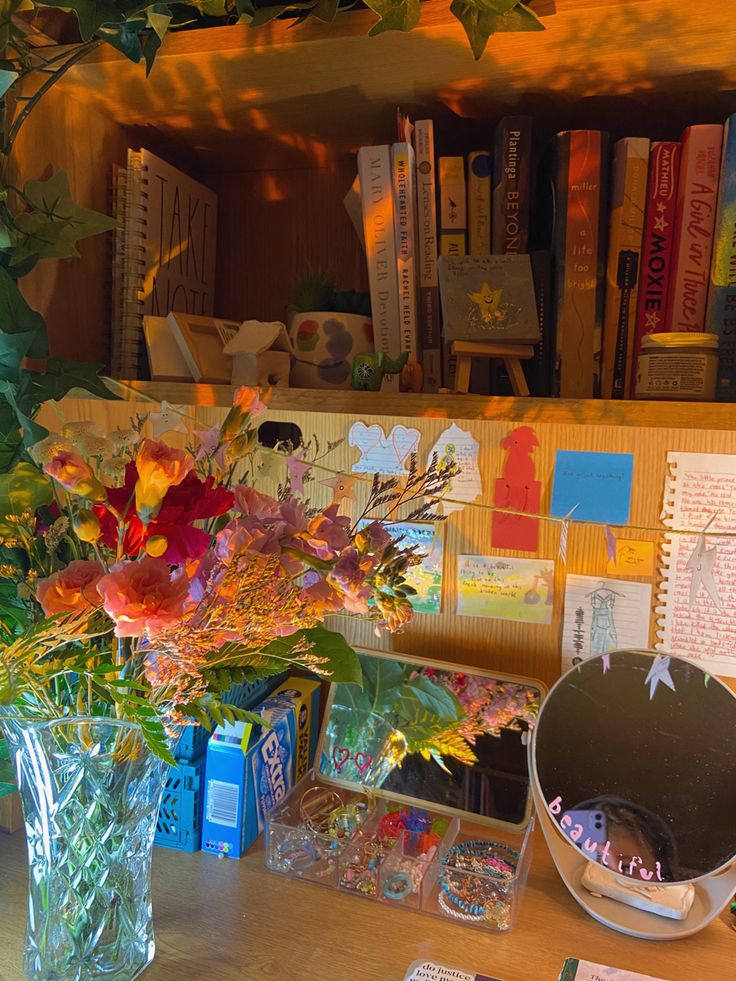 a vase filled with flowers sitting on top of a wooden table next to a book shelf