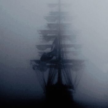 a tall ship in the fog with lots of sails on it's back end