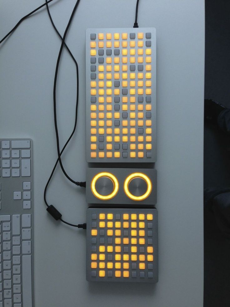 an electronic device with yellow lights on it's face and eyes, sitting next to a keyboard