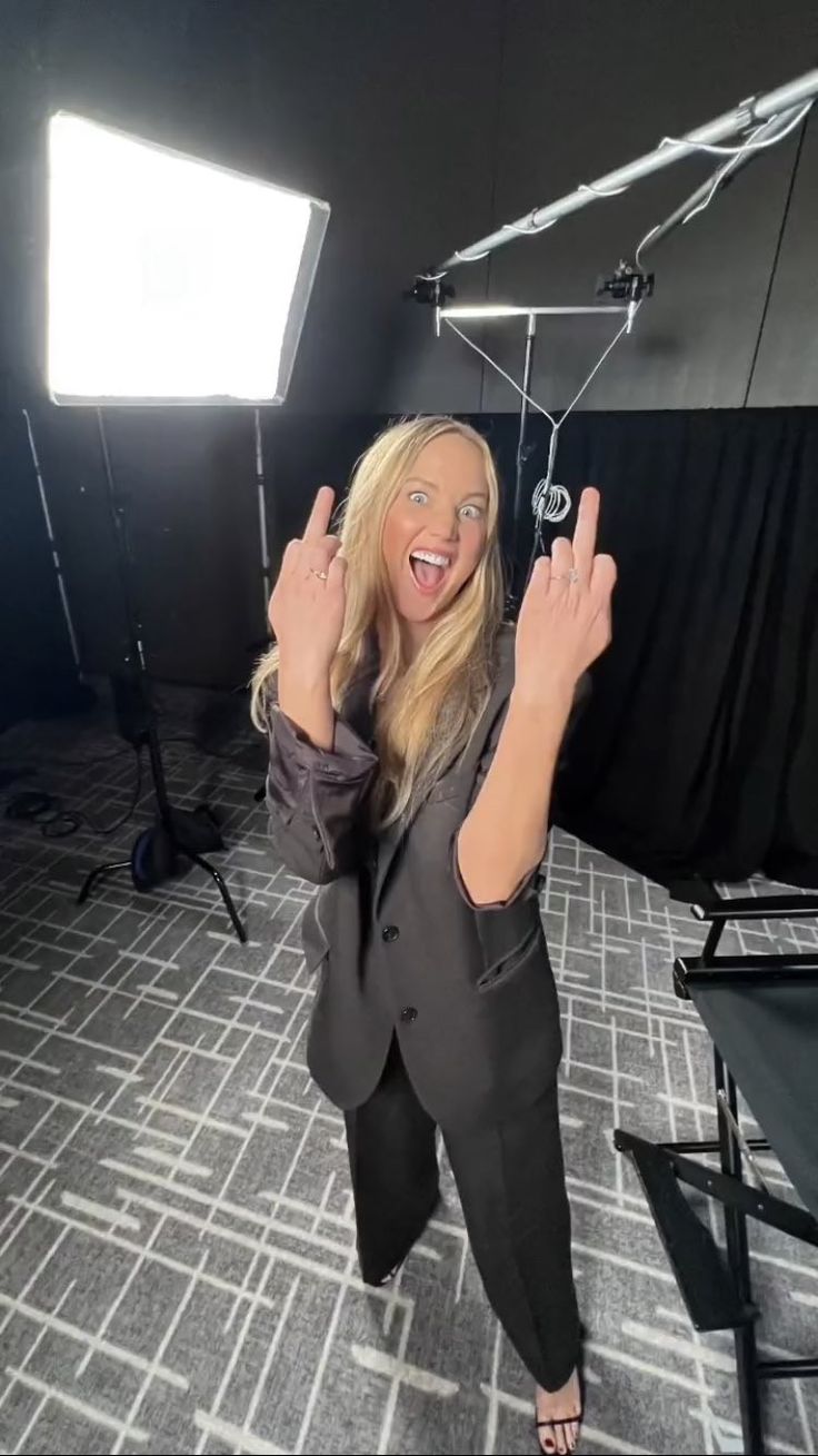 a woman standing in front of a camera with her hands up