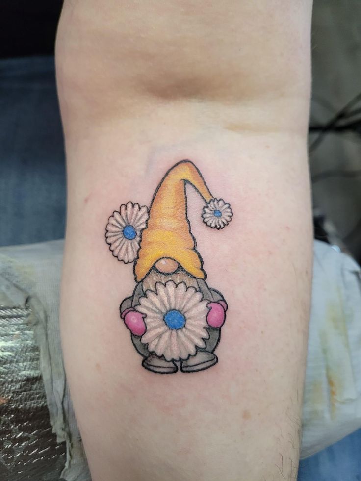 a small gnome with flowers on his leg and the word gnome tattooed on it's side