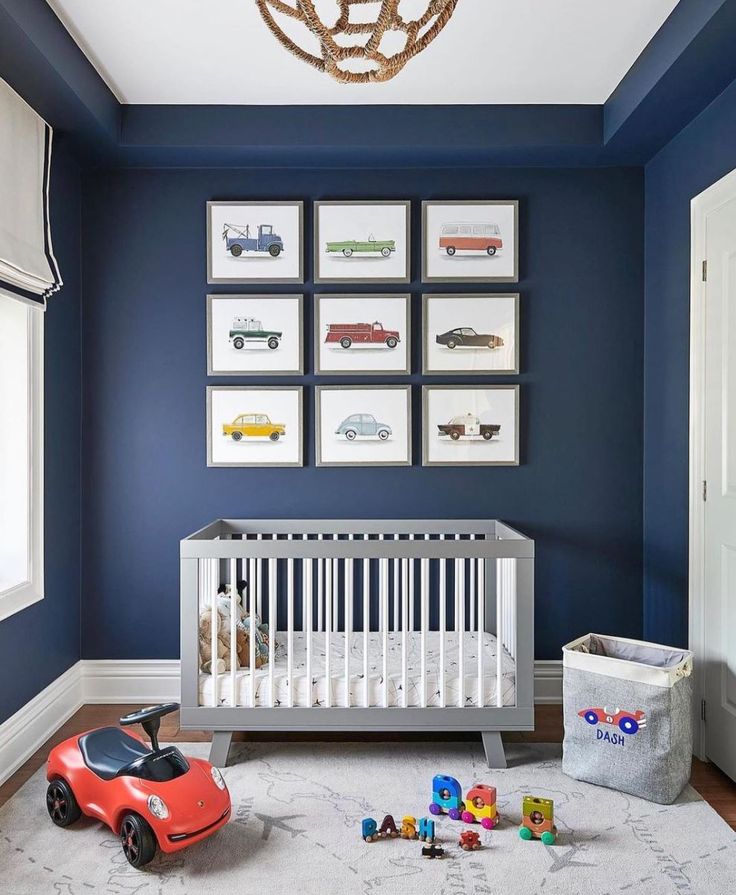 a baby's room with blue walls and pictures on the wall, including a toy car