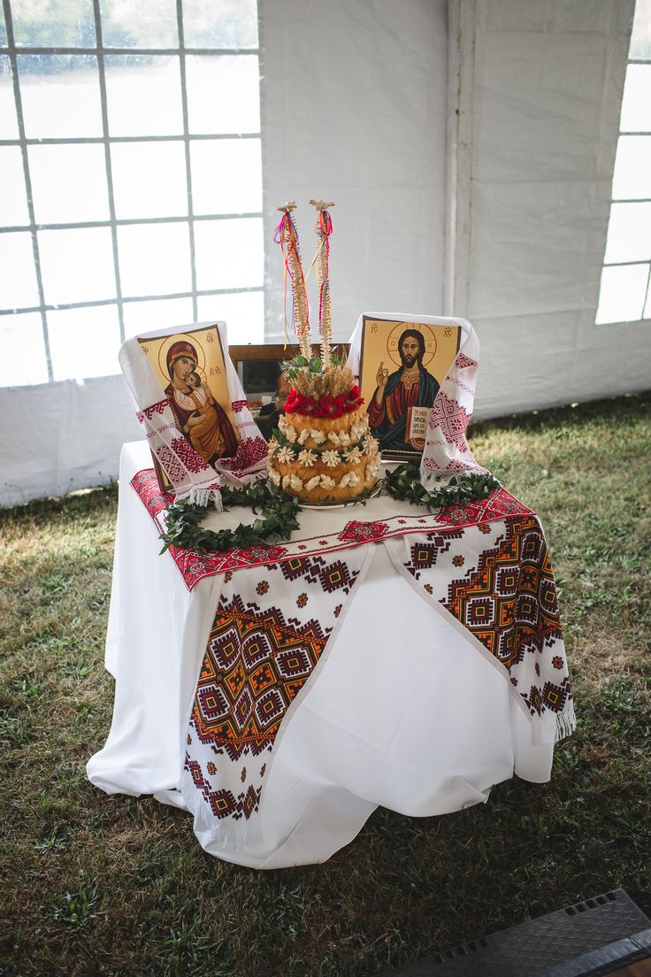 a table topped with cake and pictures on top of it in the grass next to windows