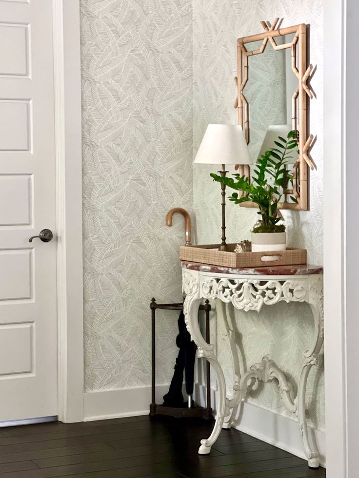 a white table with a mirror and lamp on top of it next to a door