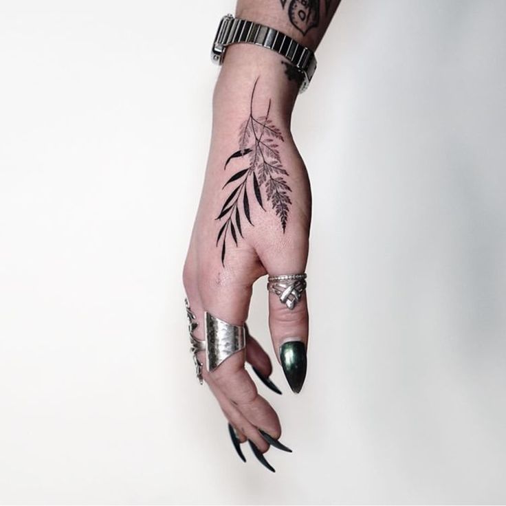 a woman's hand with tattoos and rings on it