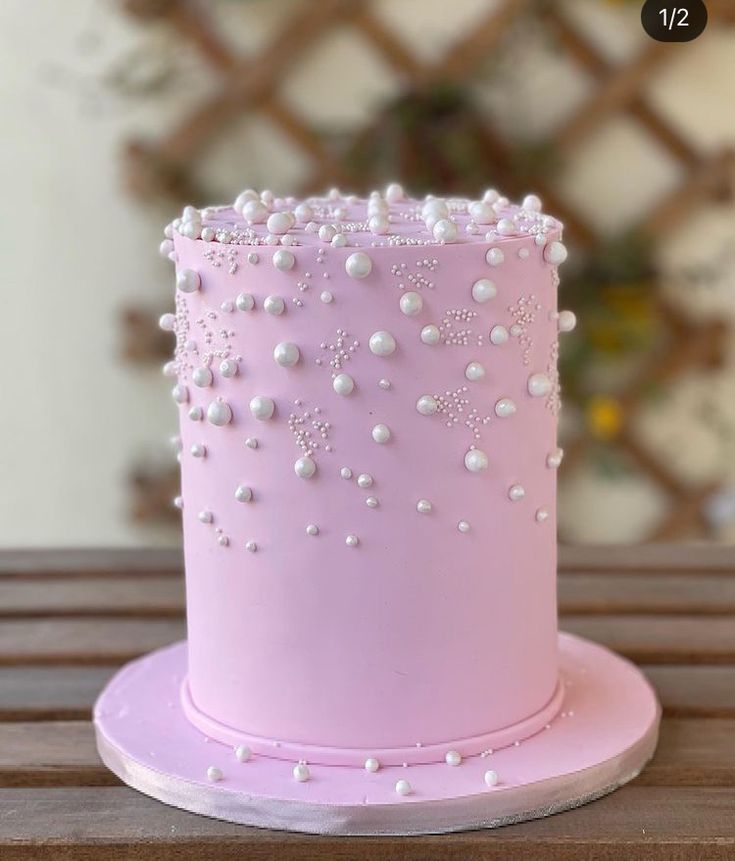 a pink cake with white pearls on it