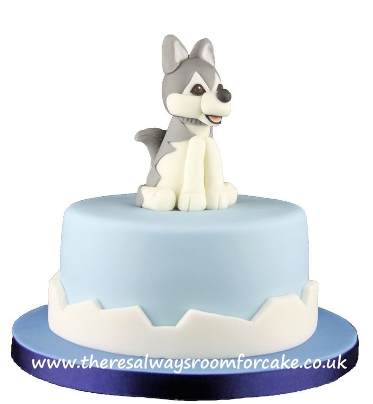 a blue and white cake with a dog figurine on top