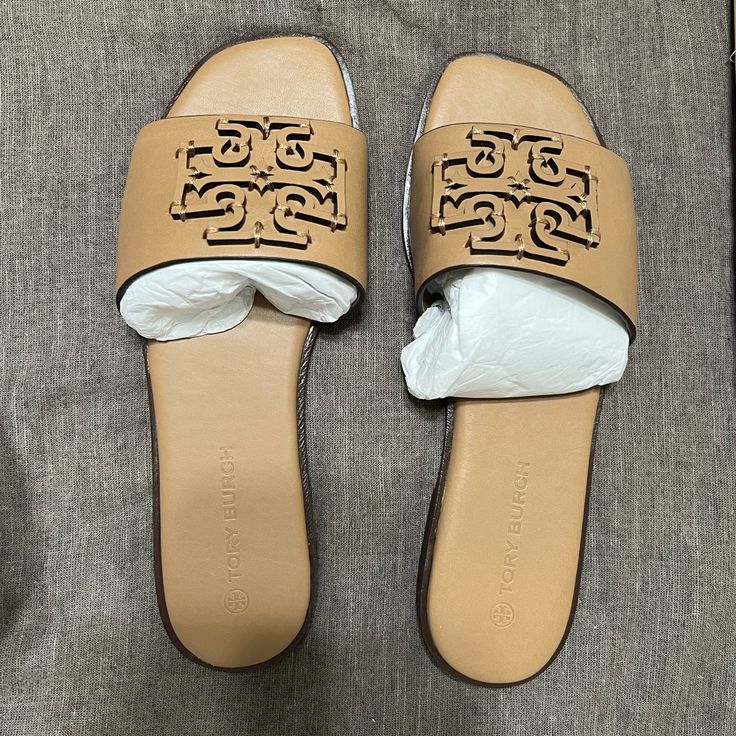 New, Never Been Used Color: Almond Flour Size: 6.5 Tan Open Toe Sandals With Cushioned Footbed, Tan Sandals With Cushioned Footbed And Flat Heel, Flat Tan Sandals With Leather Footbed, Tan Slip-on Sandals With Branded Insole, Tory Burch Slides, Navy Blue Wedges, Logo Flip Flops, Blue Wedges, Toe Ring Sandals