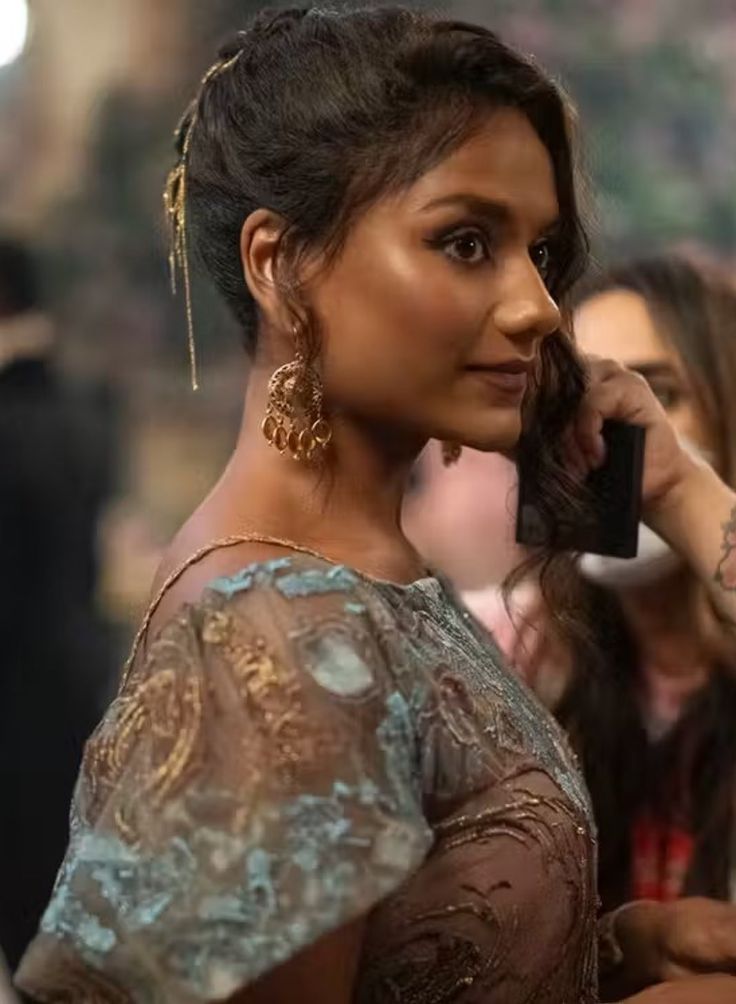 a woman talking on a cell phone while standing in front of other people at an event