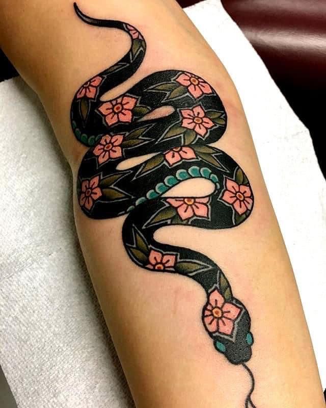 a woman's arm with a snake on it and flowers in the middle of her arm