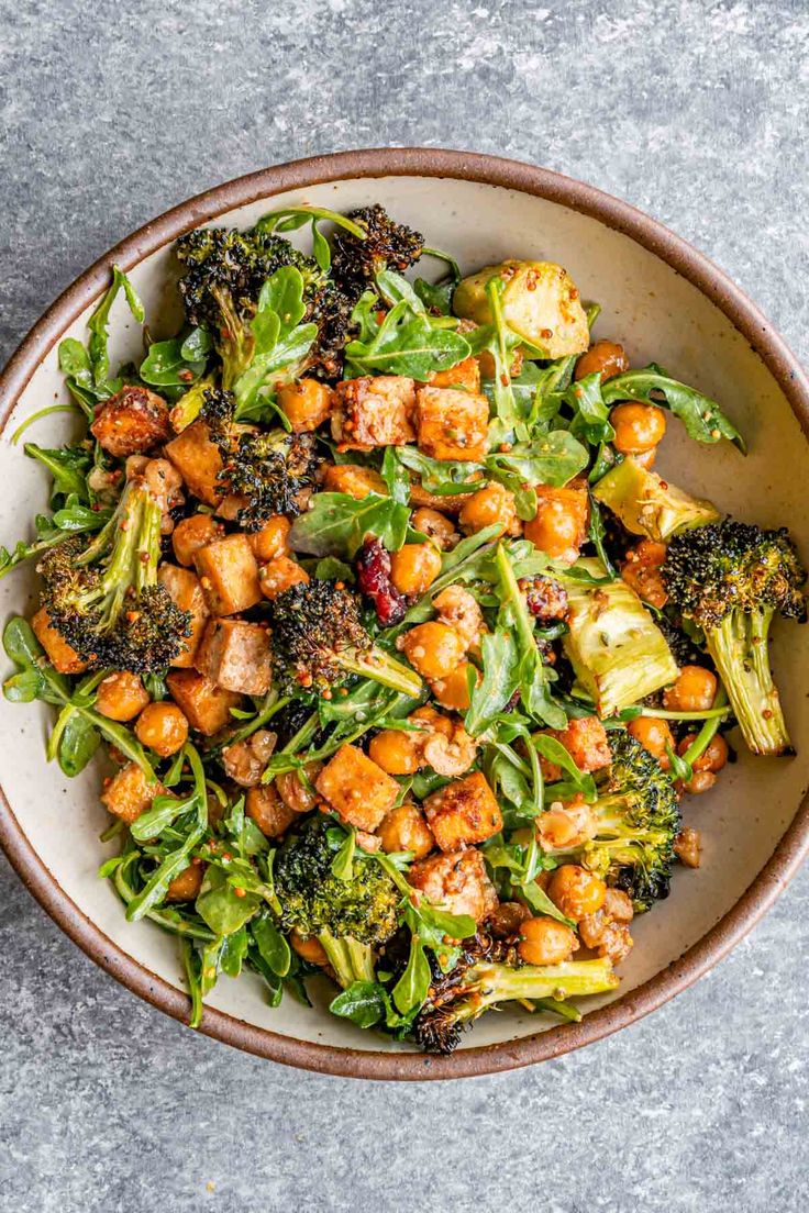 a bowl filled with broccoli, cauliflower and chickpeas on top of a table