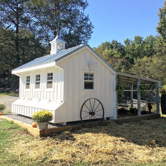 a small white building with a wheel on the front