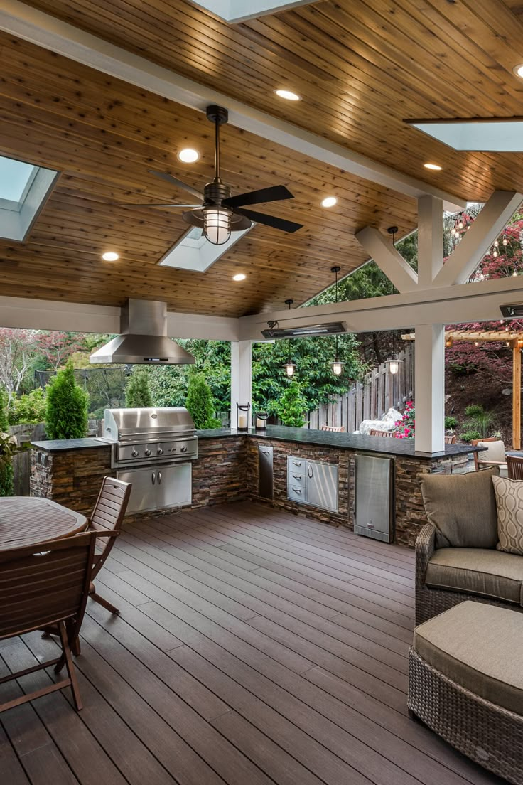 an outdoor kitchen and dining area with wood flooring, ceiling fans, and grill