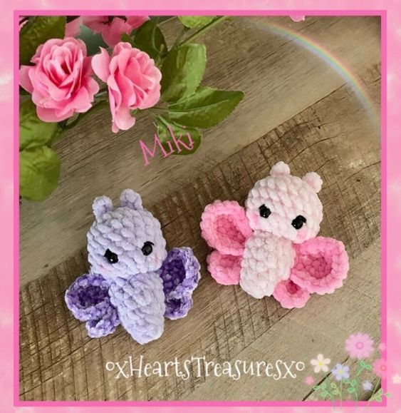 two small crocheted teddy bears sitting next to each other on a wooden table