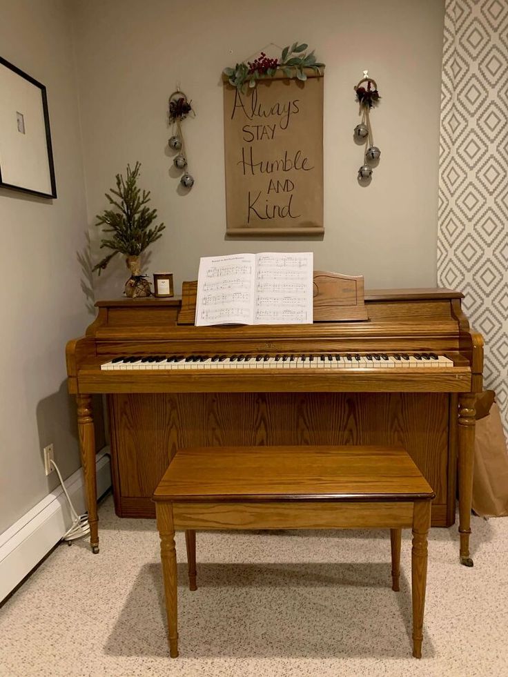 a piano and bench in a room with a christmas sign on the wall behind it