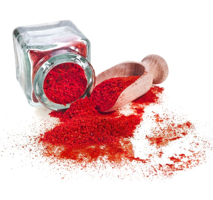 red powder spilling out of a glass jar next to a wooden spoon