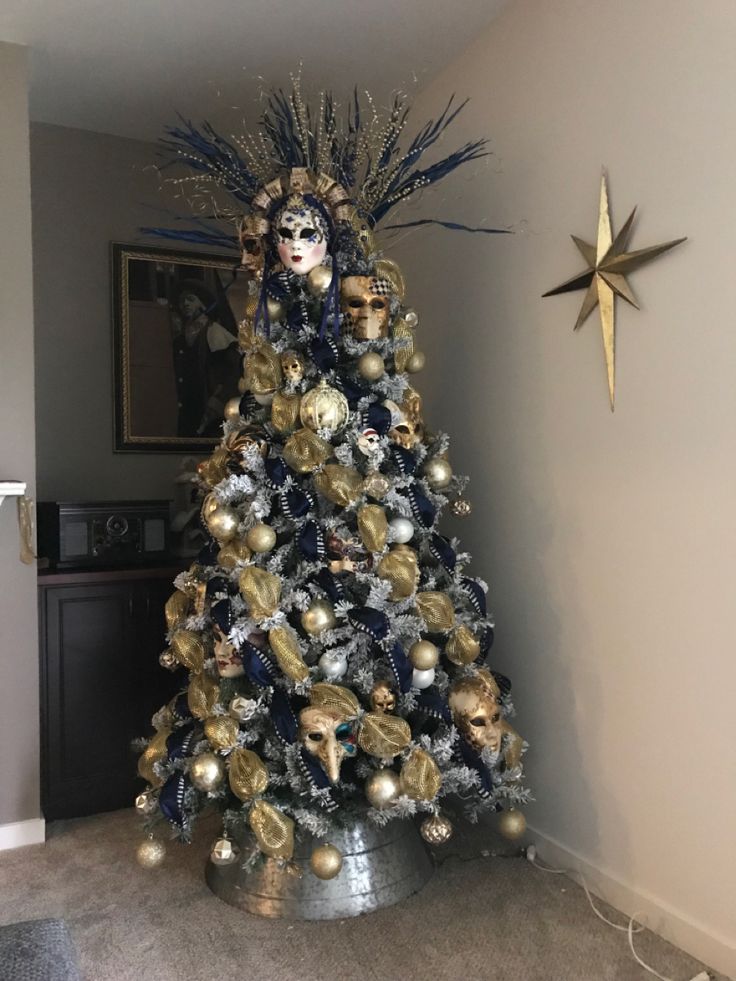 a decorated christmas tree in the corner of a room with gold and silver ornaments on it