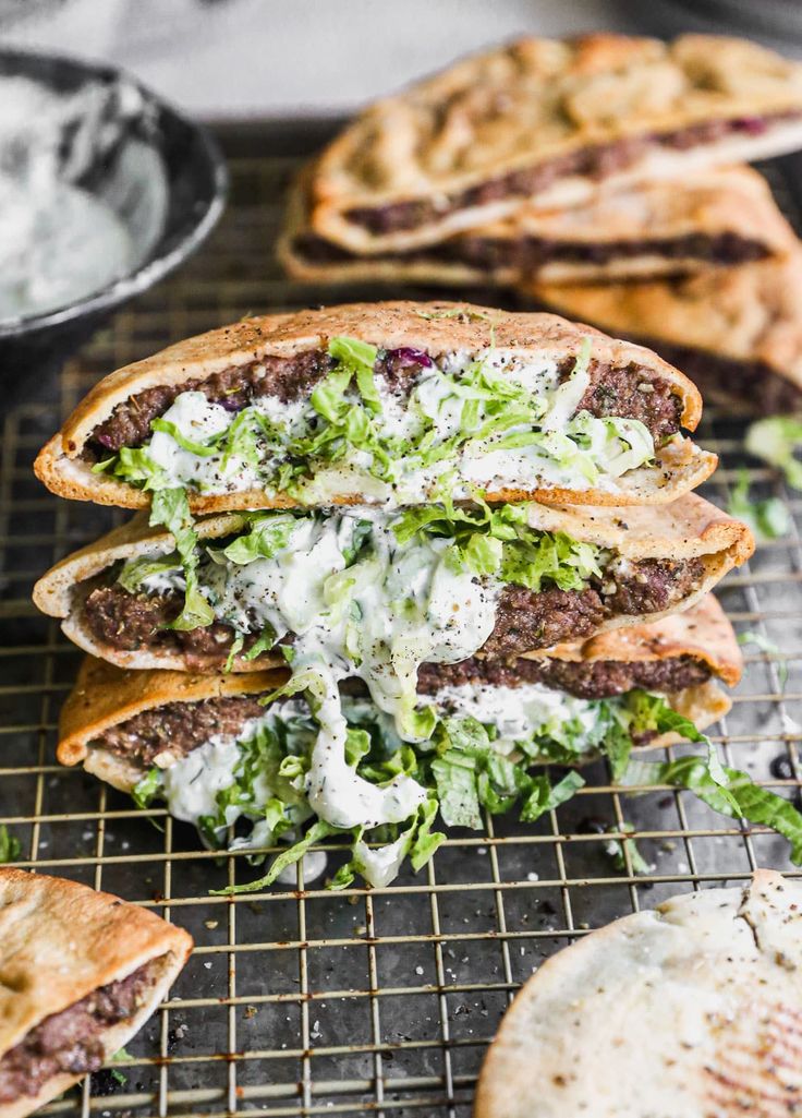 several pita sandwiches with lettuce and other toppings on a cooling rack