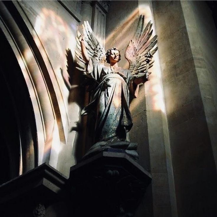 an angel statue on the side of a building with sunlight streaming through it's windows