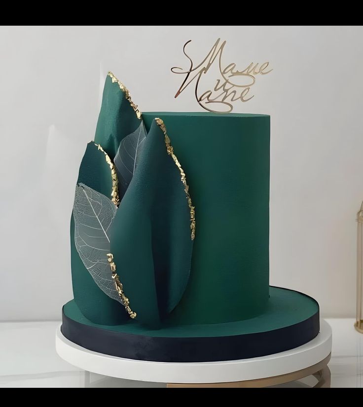 a green cake with gold leaf decoration on top