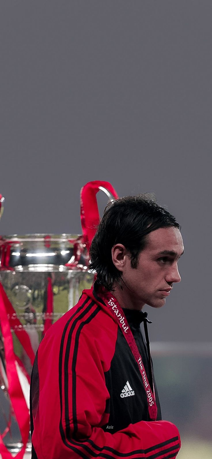 a man in red and black jacket next to a soccer trophy