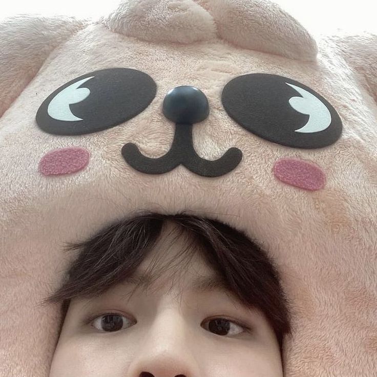 a young boy is hiding under a large stuffed animal