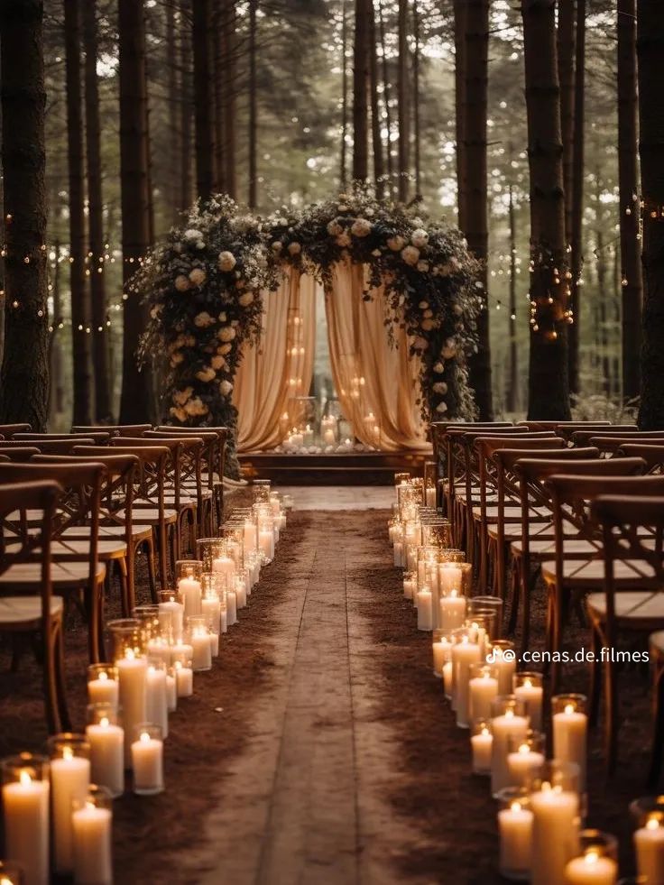 an outdoor wedding setup with candles and flowers on the aisle, surrounded by tall trees