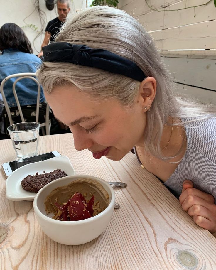 a woman eating food from a bowl on top of a table