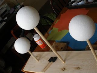 three white lamps sitting on top of a wooden table next to an orange and black object