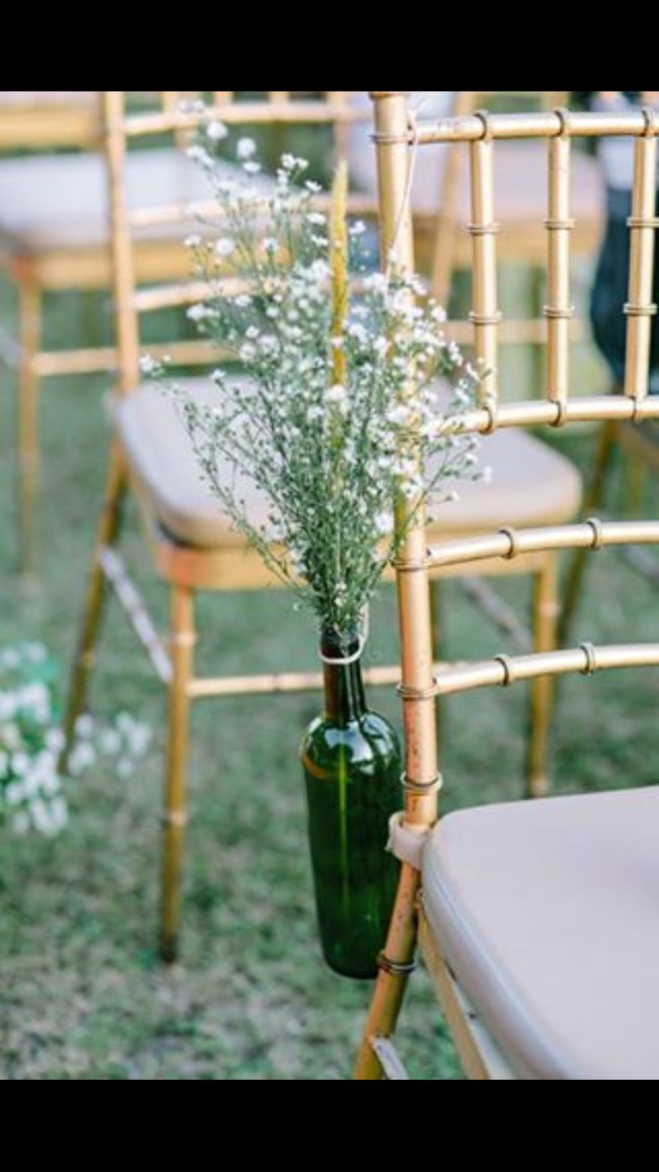 flowers are in a green vase on the back of chairs