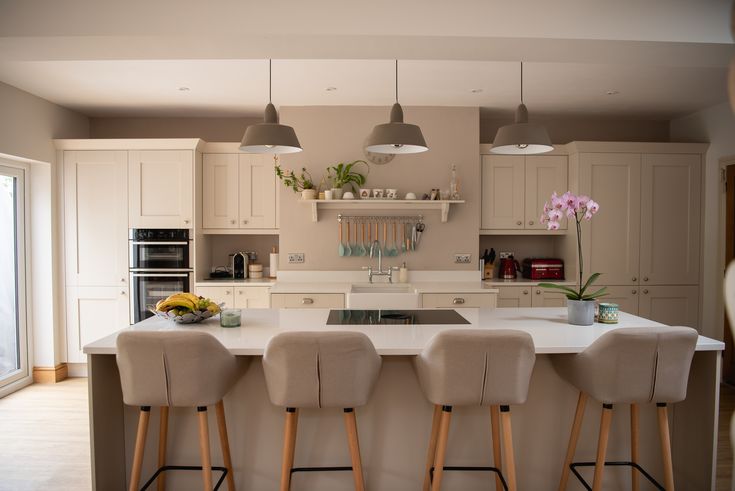 a kitchen with four stools in front of an island and three lights above it