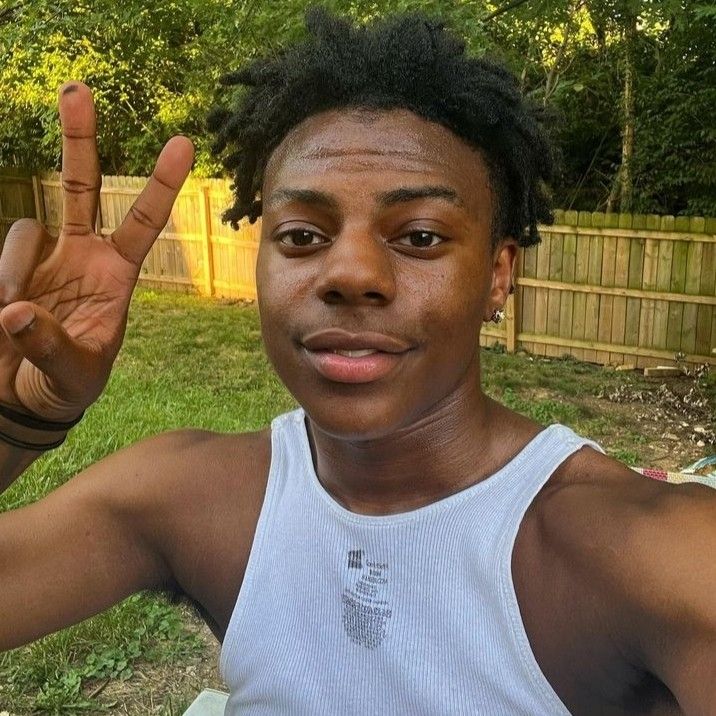 a man with dreadlocks making the peace sign in front of his face and wearing a white tank top