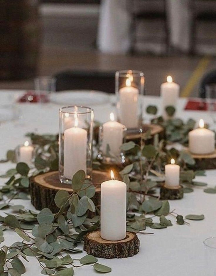 a table topped with lots of candles and greenery