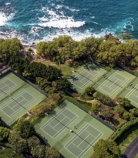 an aerial view of two tennis courts and the ocean