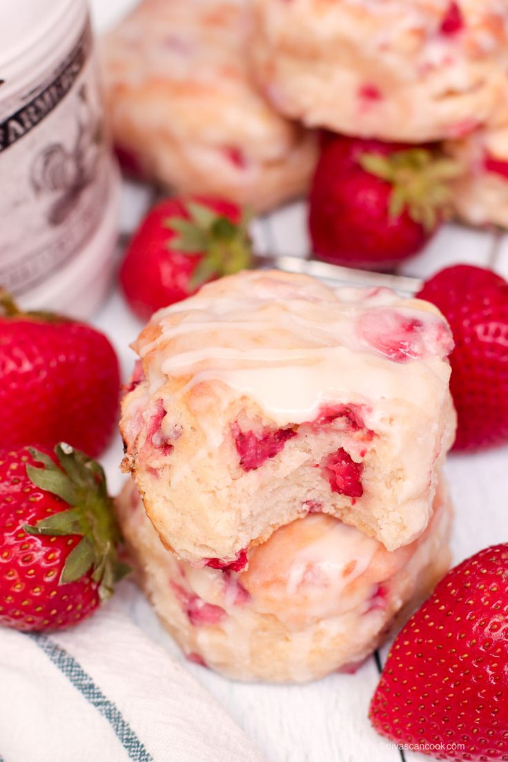 some strawberries are sitting on a towel next to muffins with icing